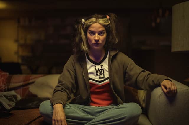 Annie Murphy as Joan in Black Mirror Season 6 episode 1 'Joan is Awful', cross legged on the sofa (Credit: Nick Wall/Netflix)