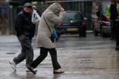 People walk in rain and high winds.