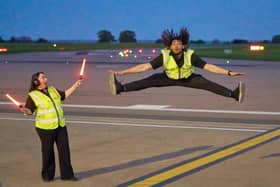 Airport ground handlers perform lively dance routine on runway.