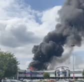 Flames rage through factory as plumes of smoke rise into air.