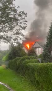 Flames pour from house roof after it’s struck by lightning.