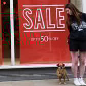 A woman and her pet dog stand outside a FatFace store in Winchester (Photo: ADRIAN DENNIS/AFP via Getty Images)