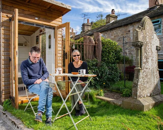Bob Sutton and Nubia enjoy a cup of tea in the back garden of their cottage beside a huge grave and tombstone.