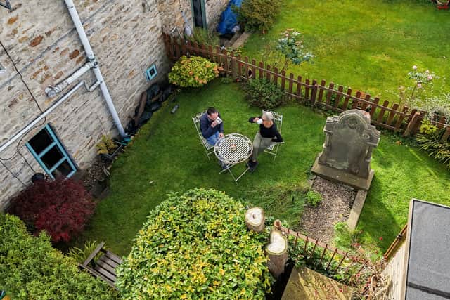 An aerial view of Bob Sutton and Nubia enjoying a cup of tea in the back garden of their cottage beside a huge grave and tombstone.