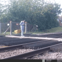 Teen stares at phone while stood on level crossing. Network Rail 