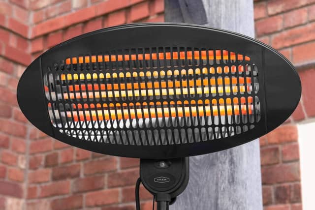 Harrier 2000W outdoor patio heater glowing orange, mounted on a stand against a brick wall