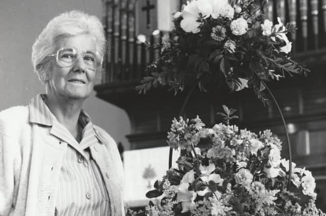 Noreen McBay, pictured in August, 1989, with one of her floral arrangements at the Knox's Church Flower Festival. It was called A Little Child The Saviour Came, and was positioned on the baptismal font.