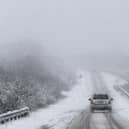 Car drives along snowy road.