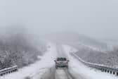 Car drives along snowy road.