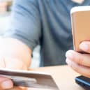A person looks at their bank card and mobile phone. PIC: Alamy/PA