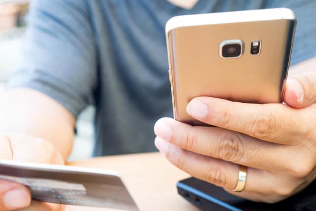 A person looks at their bank card and mobile phone. PIC: Alamy/PA