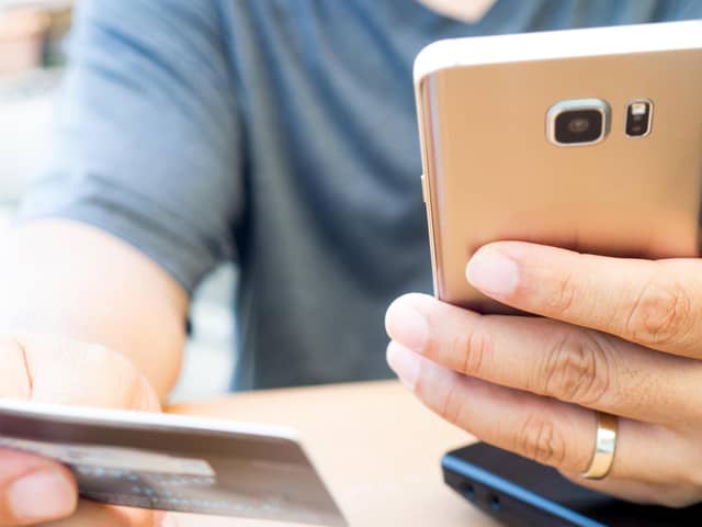 A person looks at their bank card and mobile phone. PIC: Alamy/PA