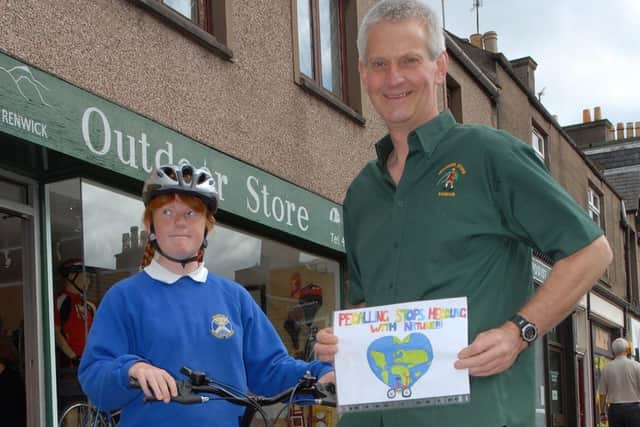 Andrew Renwick at his Outdoor Store in Forfar in June, 2006, with an award-winning poster and its artist from Muirfield Primary, Arbroath.