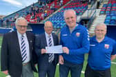 Pictured are Supporter Club members Stephen McCallum and Kevin Watson presenting the cheque to John and Club Honorary VP Malcolm Watters.