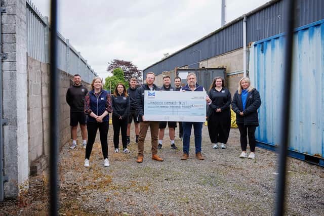 Standing with the £200,000 Cheque: Chris Platt (CEO of Montrose Community Trust) and Tom Hutchison (CEO of Montrose Port). Surrounded by Montrose Community Team and Catriona Innes of Montrose Port. Background is the Links Park stand that the new Gable End facility will replace.