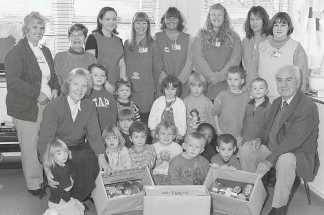 ​In October, 1998, Angus College Nursery children presented gifts of food for the Town Mission, which were accepted by the Missionary, Dr Bob Clapham, right front.