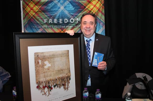 Alba leader Alex Salmond posing next to "The Wee Alba Book" and a copy of "The Deceleration Of Arbroath".